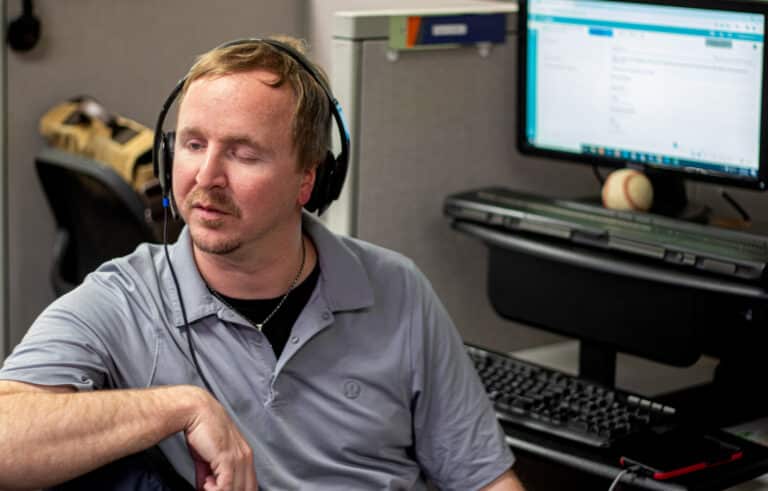 Cameron leans back in his chair while working in the Alphapointe Call Center. 