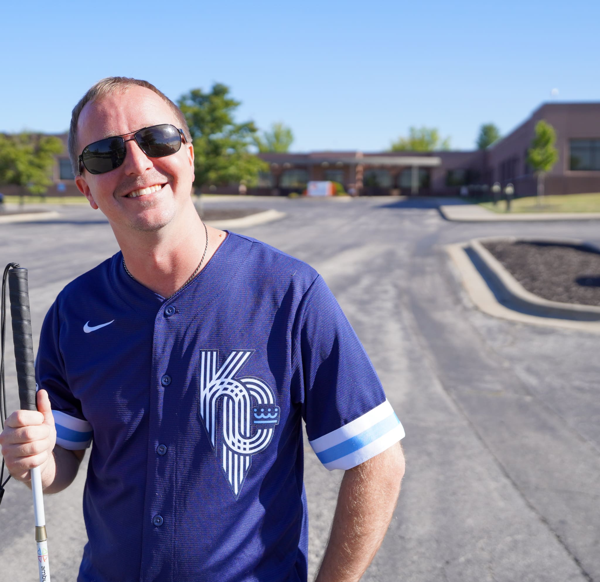 Cameron, in a blue Kansas City shirt, stands in front of the Alphapointe offices.