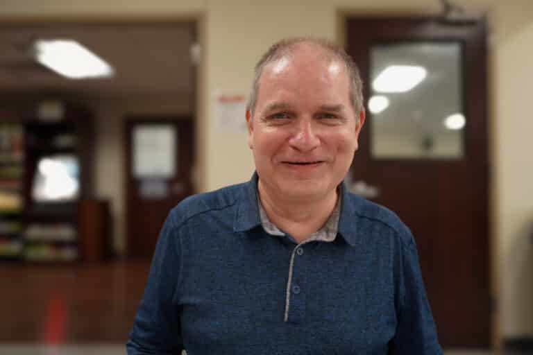 Randy is pictured in the Alphapointe entry area. He is smiling at the camera.