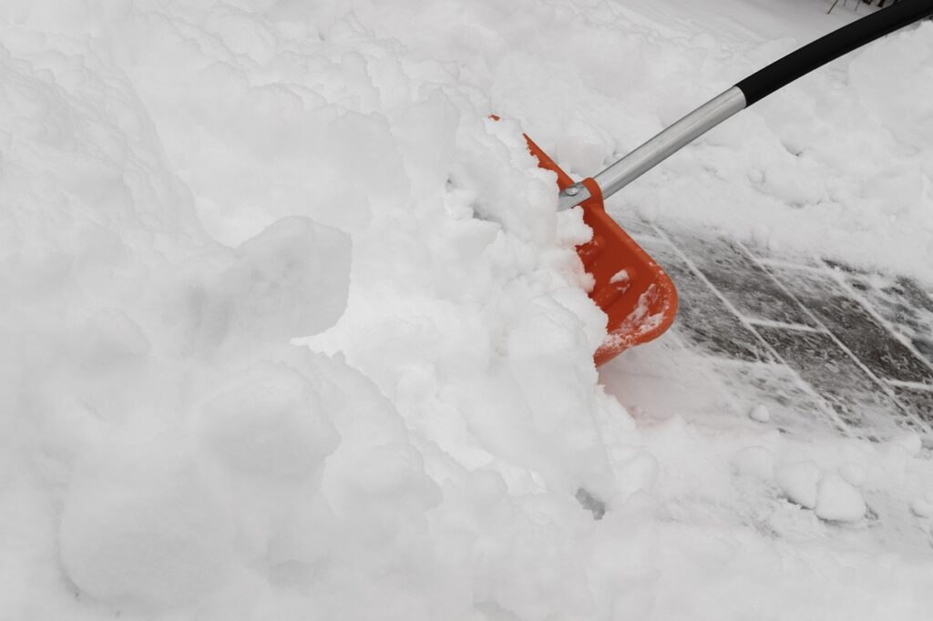 A snow shovel is moving snow. 