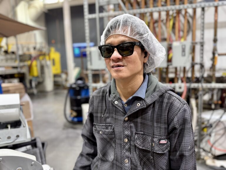 Thomas is smiling at the camera while working in the Alphapointe Plastics Department.