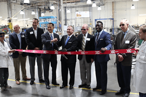 Group ribbon cutting featuring from L to R: Express Scripts representatives; CEO, Reinhard Mabry; Foundation Board Chair, David Westbrook; Councilman, Jermaine Reed; Board Chair, Ed Marquette. All standing in our plastics department cutting a ribbon to launch our partnership with Express Scripts.