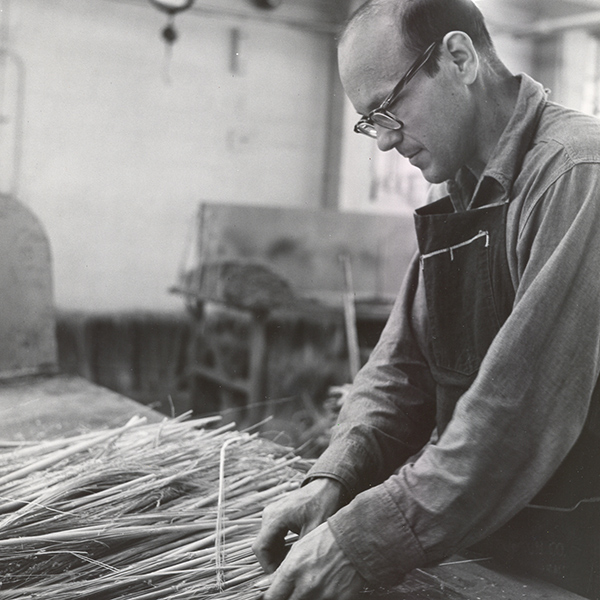 Black and white image of a male employee in the broom workshop in the late 60's