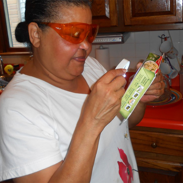 Image of Angela using a magnifier to read the microwave instructions on a frozen meal