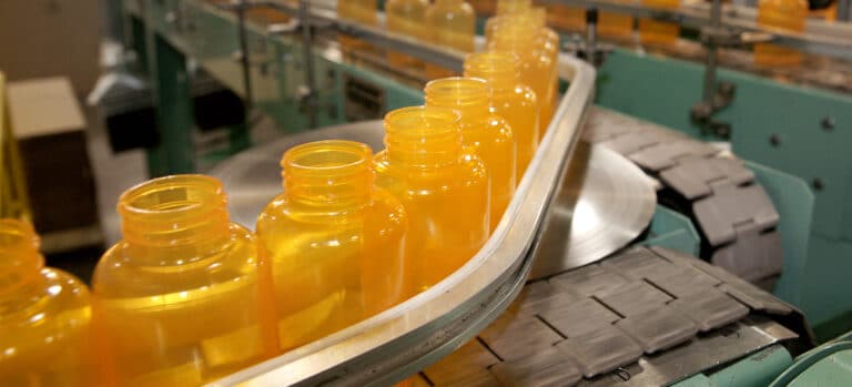 Amber resin bottles in a row on a conveyor belt.